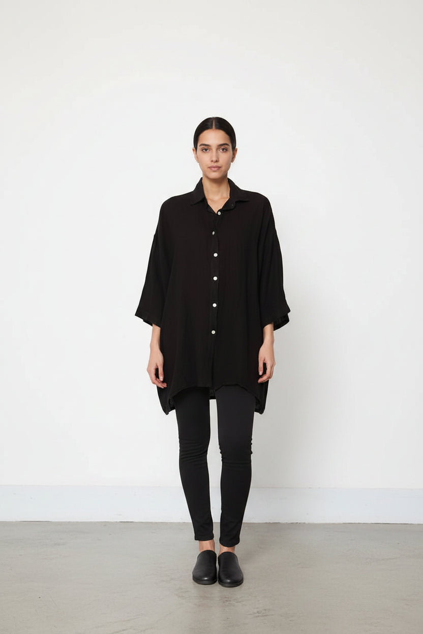 Person wearing a black button-up shirt with a white background