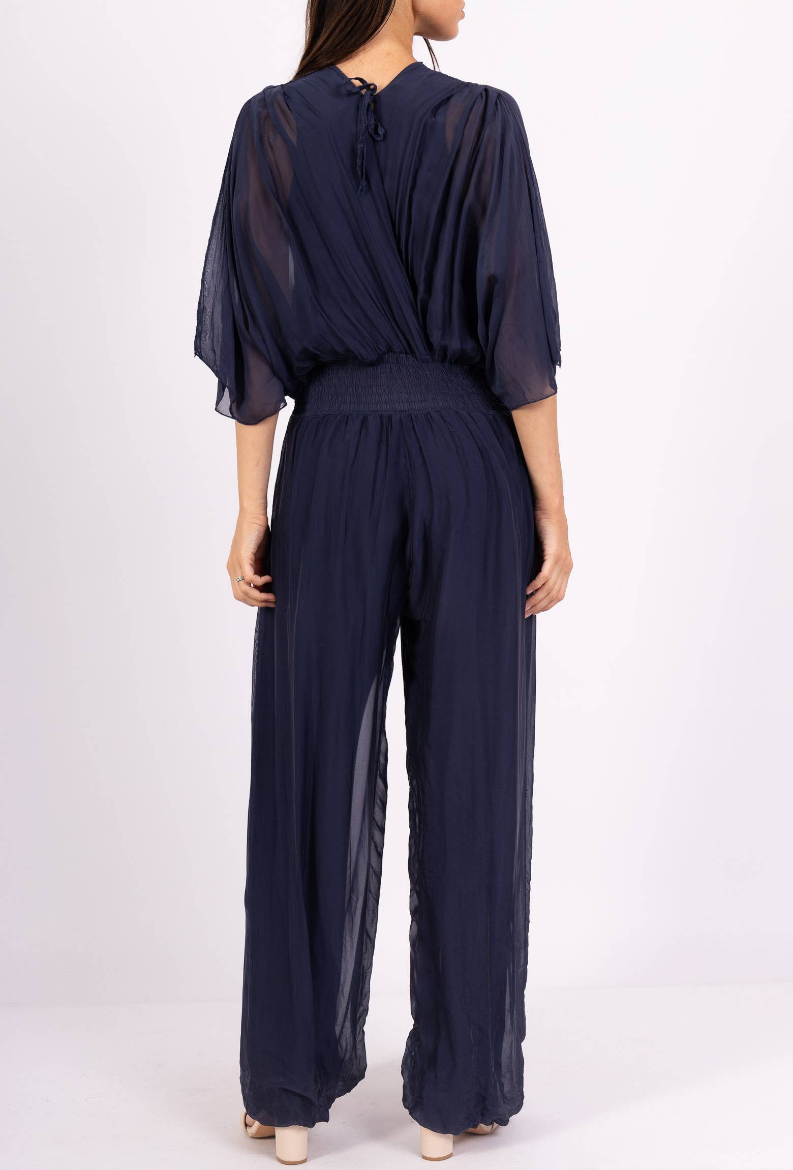 Navy blue jumpsuit with sheer sleeves on a white background