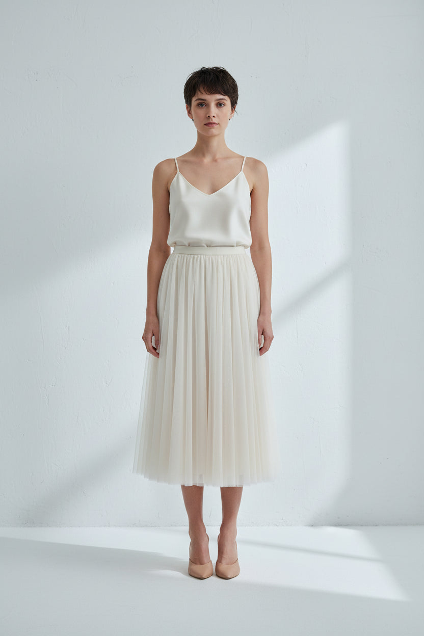 Beige pleated skirt worn by a person on a white background