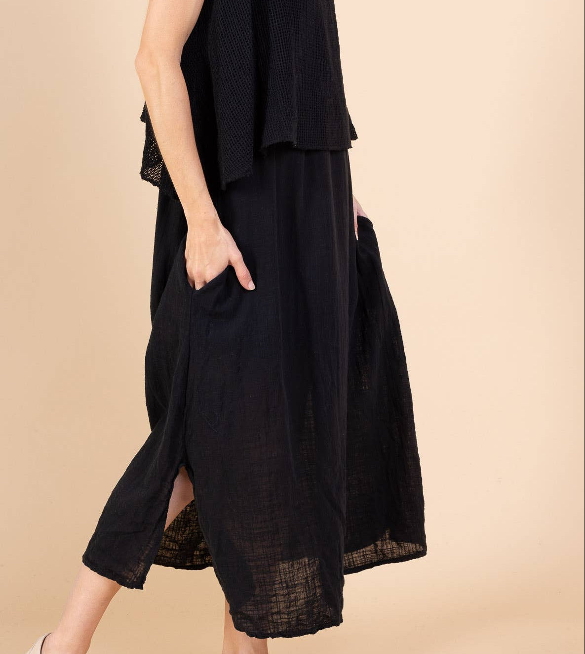 Woman wearing a black sleeveless dress on a beige background
