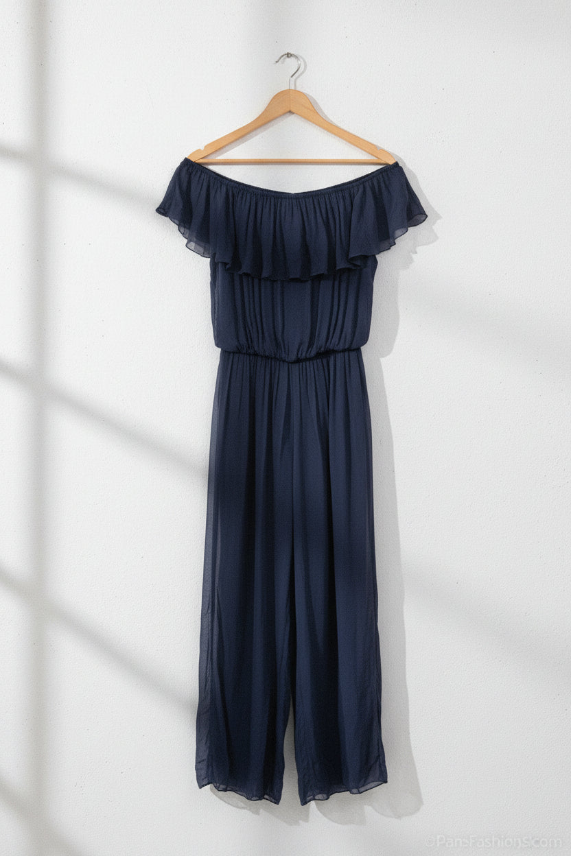Woman wearing a navy off-shoulder jumpsuit on a white background