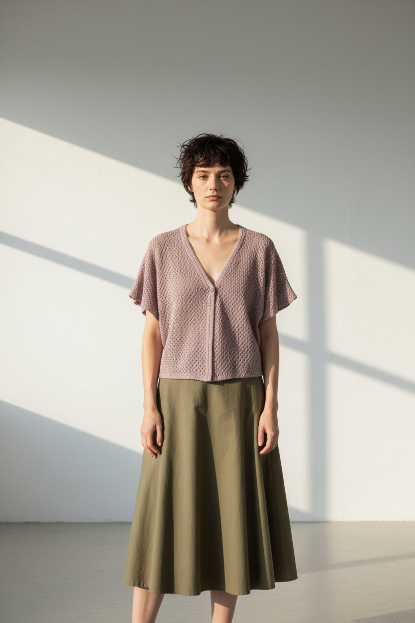 Pink crochet top on a hanger against a white background